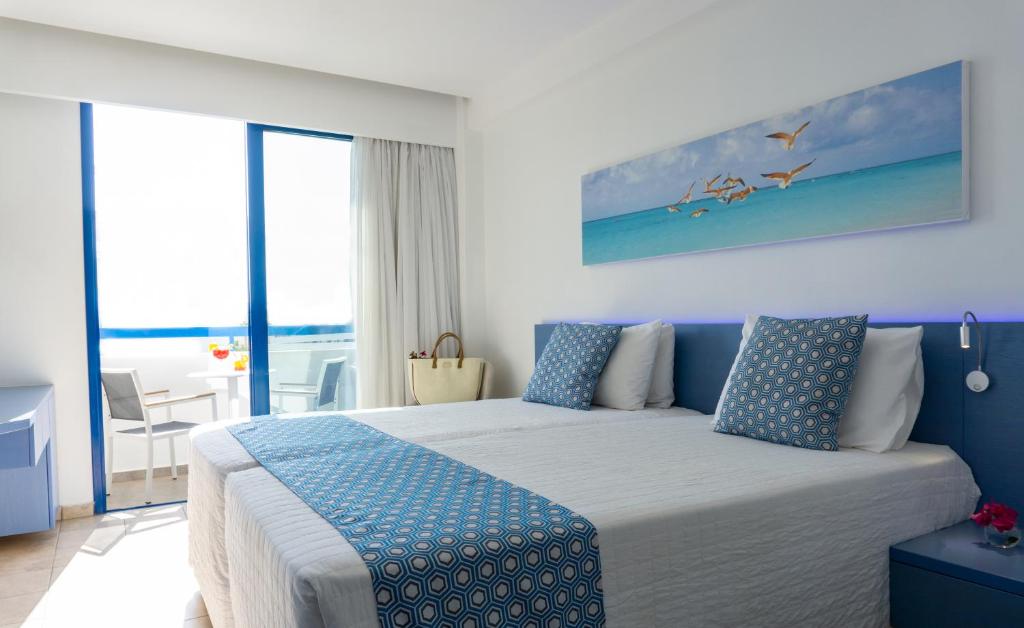 a bedroom with a large bed with blue accents at Anonymous Beach Hotel (Adults 16+) in Ayia Napa