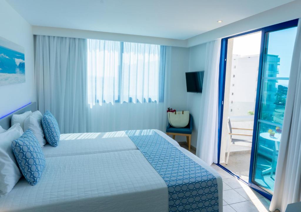 a bedroom with a large bed and a balcony at Anonymous Beach Hotel (Adults 16+) in Ayia Napa