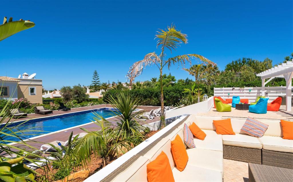Vida Boa Lodge في لاغوس: فناء مع وسائد برتقالية وزرقاء بجوار حمام سباحة