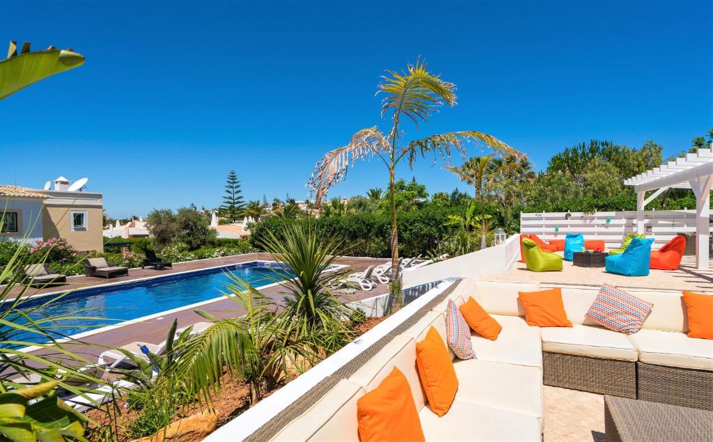 a patio with orange and blue pillows next to a pool at Vida Boa Lodge in Lagos