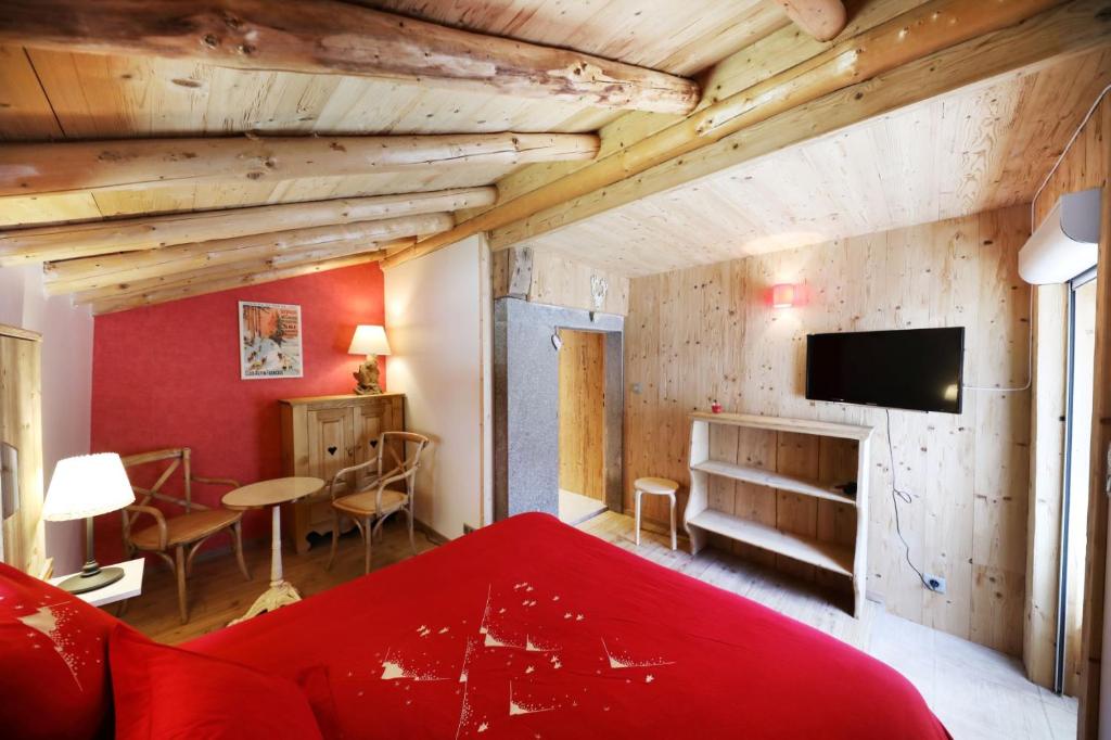 1 dormitorio con cama roja y sala de estar en Les chalots de Gérardmer, Chambre d'Hôtes, en Gérardmer