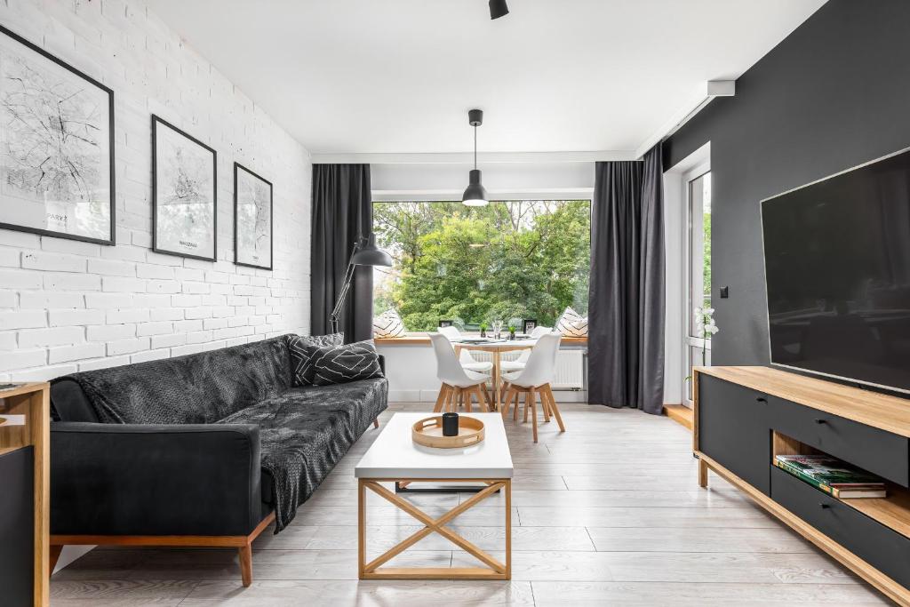 a living room with a black couch and a table at Apartamenty Solny Brzeg by Renters Prestige in Kołobrzeg