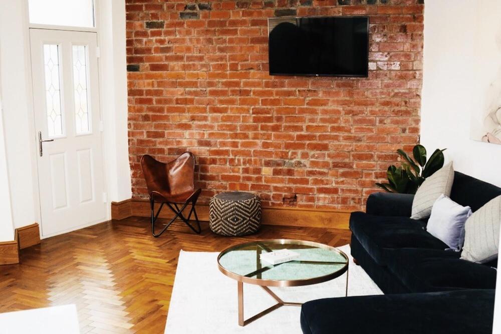 a living room with a couch and a brick wall at Newly refurbished apartment in Chapel Allerton, Leeds in Moortown