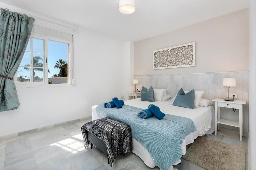 1 dormitorio blanco con 1 cama grande con almohadas azules en Stunning apartment metres from the beach - RDR222, en Marbella