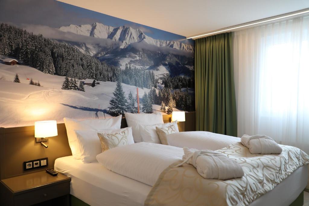 オーバーサクセンにあるAlpenlodge Val Grondaのベッド2台が備わる客室で、壁には絵画が飾られています。