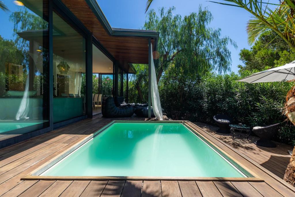 una piscina en una terraza de madera con una casa en Villa Lares en Cala Mendia