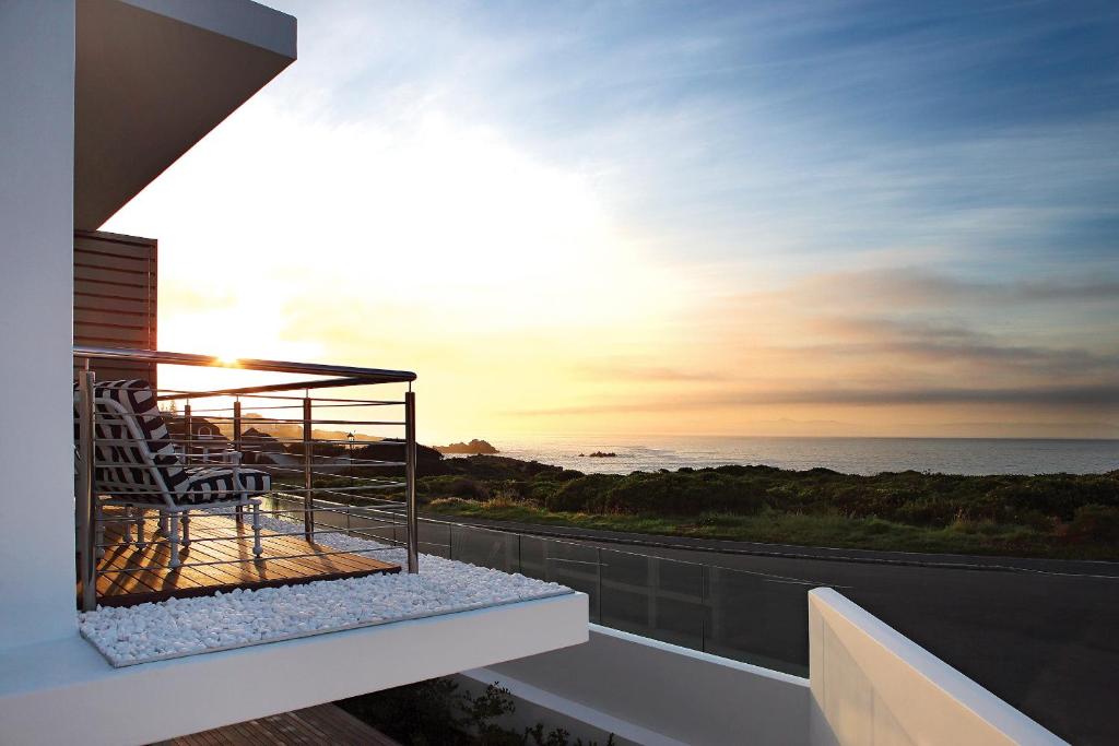 a balcony with a chair and the ocean at sunset at One Marine Drive Boutique Hotel & Spa by The Living Journey Collection in Hermanus