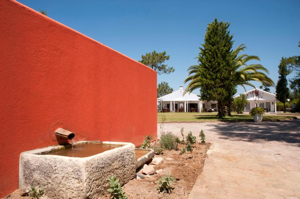 uma parede vermelha com uma fonte de água em frente em Casal do Frade em Sesimbra