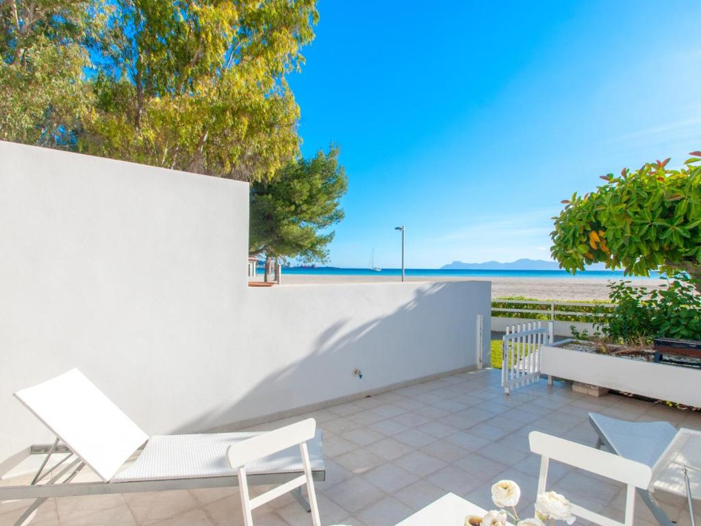 a patio with white chairs and a view of the beach at Apartment Oiza Sand Castles 23 at Alcudia Beach, WIFI and aircon in Alcudia