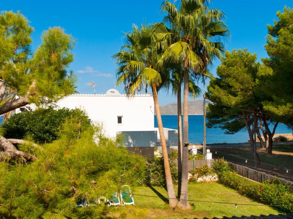 une maison blanche avec des palmiers et des chaises dans l'établissement Villa Tita de Manresa, con jardines y vista mar, à Alcúdia