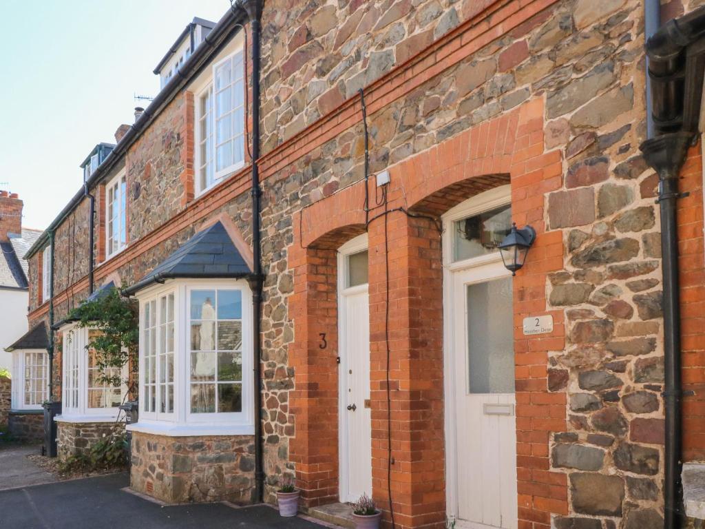 un edificio de ladrillo con una puerta y ventanas blancas en 3 Lowerbourne Terrace, en Minehead