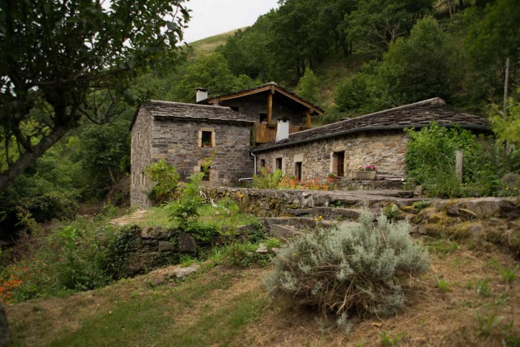 una vieja casa de piedra en una colina con árboles en El Molino de Yera en Vega de Pas