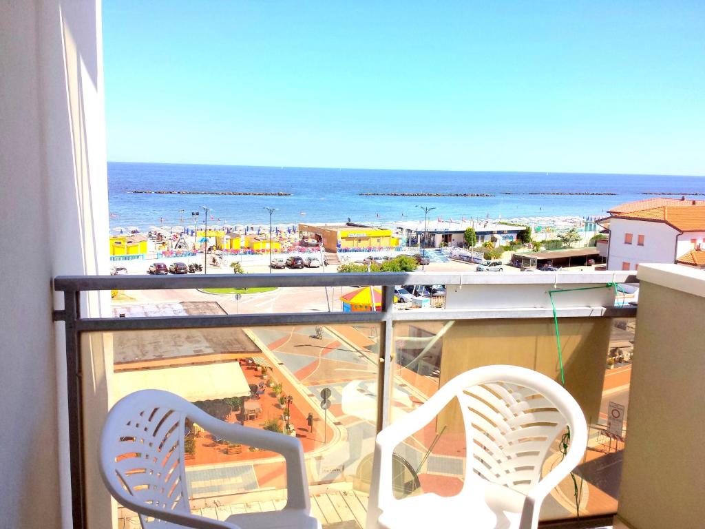 balkon z 2 krzesłami i widokiem na plażę w obiekcie Cortina 1-46 w mieście Lido di Pomposa