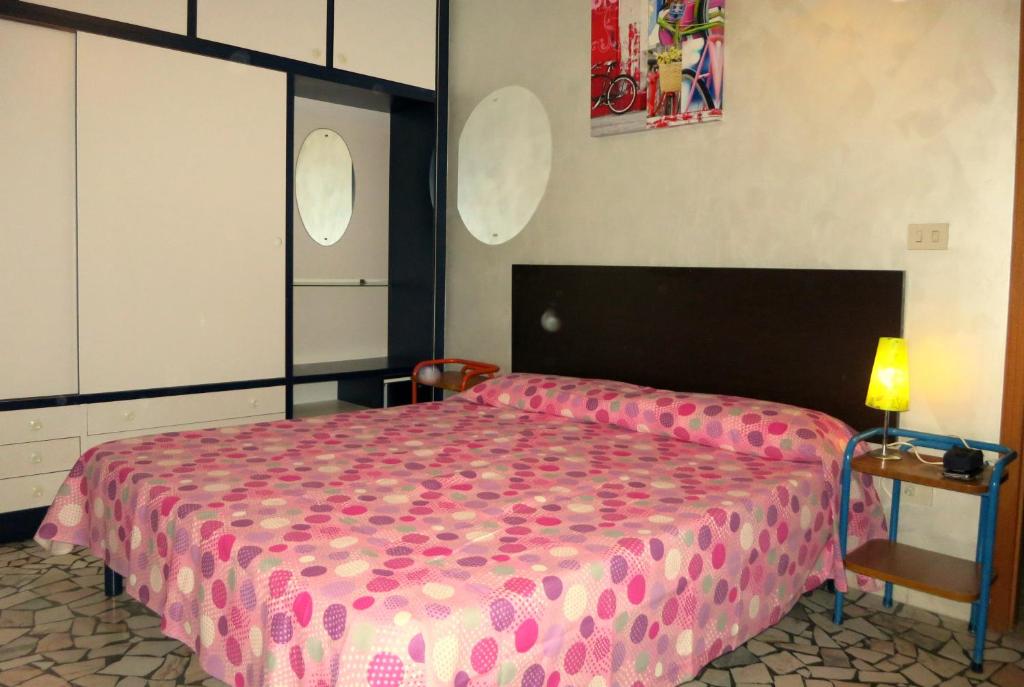 sypialnia z łóżkiem z różową narzutą w obiekcie Cortina 1-46 w mieście Lido di Pomposa