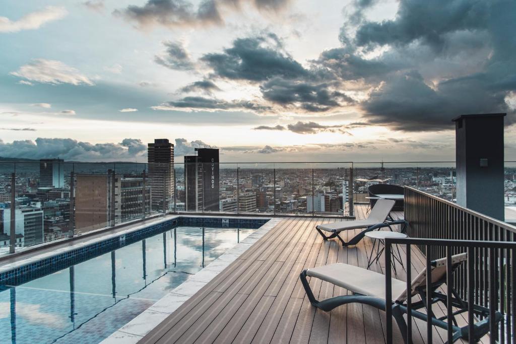 einen Balkon mit Pool und Stühlen auf einem Gebäude in der Unterkunft Spotty Bogotá Centro in Bogotá