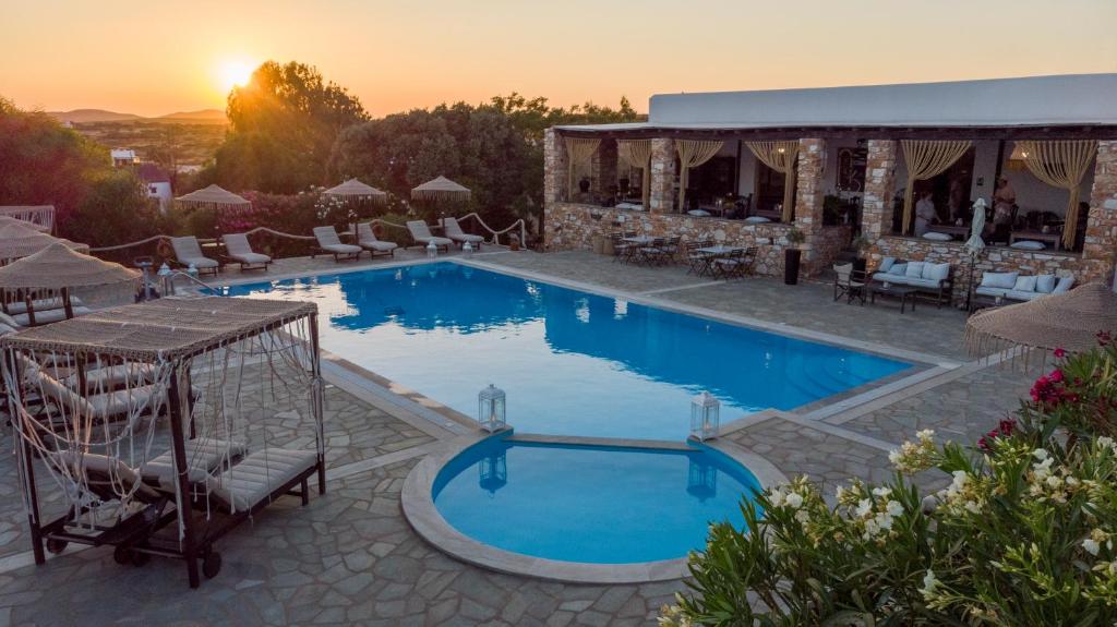 a large swimming pool with a sunset in the background at Parosland Hotel in Aliki