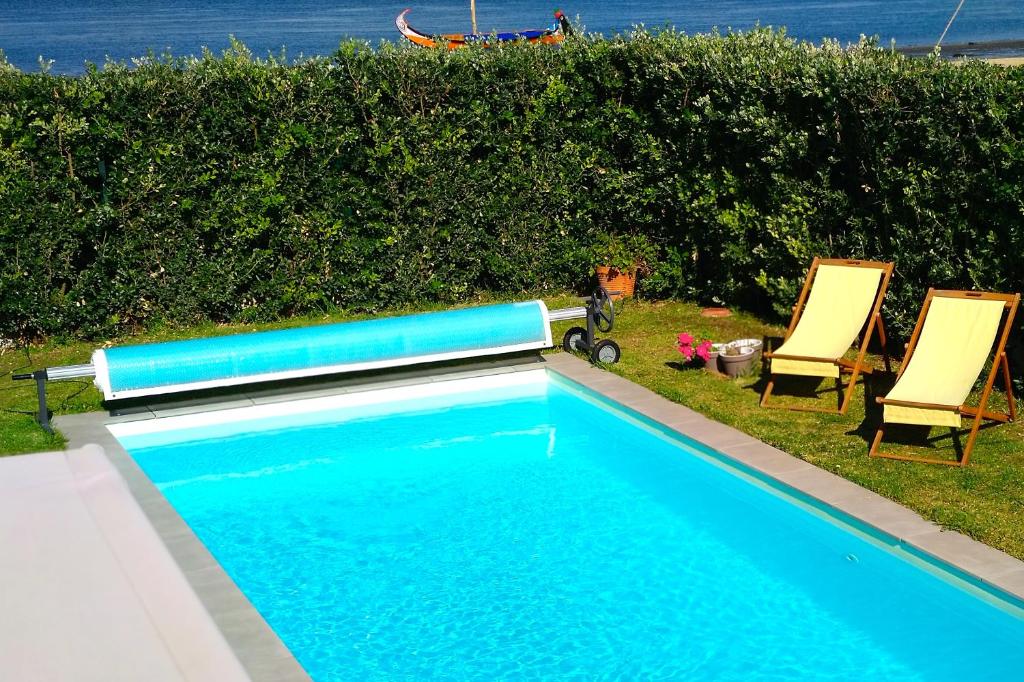 a swimming pool with two lawn chairs at Casa Gaivina 1 in Torreira