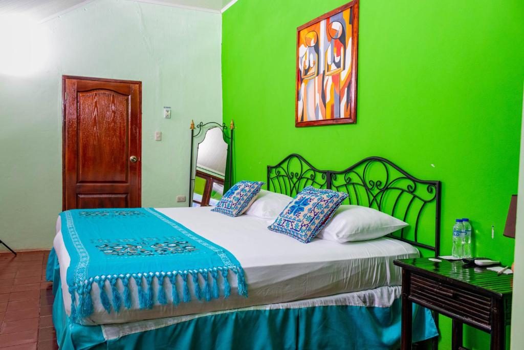 Dormitorio verde con cama y pared verde en Rual's Hotel, en Somoto