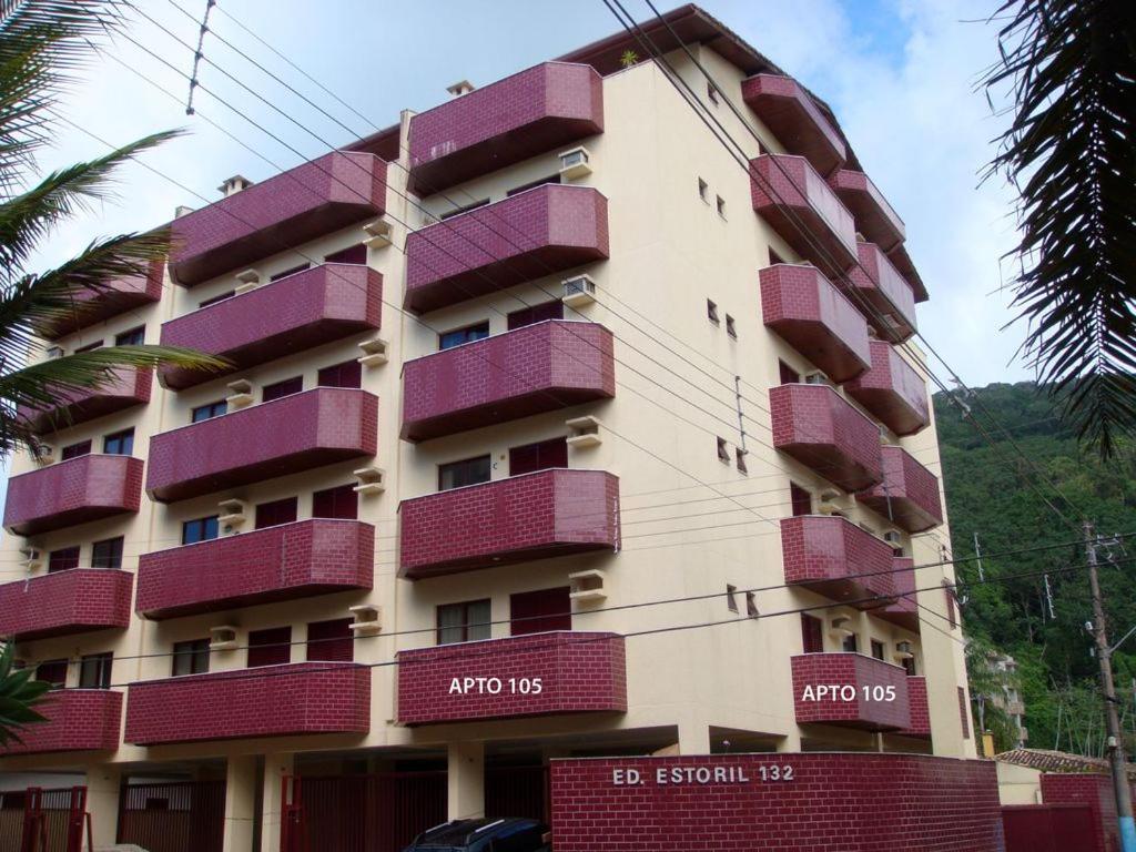um edifício alto com varandas roxas em Apartamento espaçoso com ar condicionado e Wi-fi, a 100 metros da praia - Edifício Estoril em Ubatuba