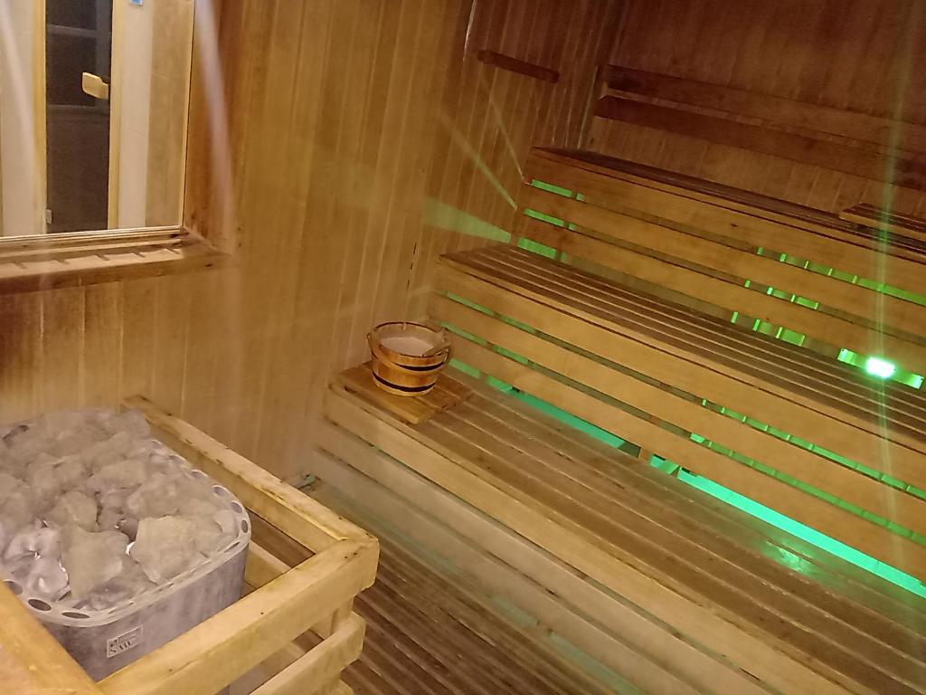 a sauna with a bench and a bucket of rocks at Gabi & Gabi Apartments in Hajdúszoboszló