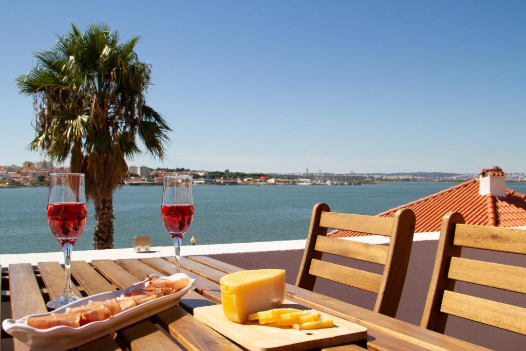 una mesa de madera con dos copas de vino y queso en Seixal Bay Apartments en Arrentela