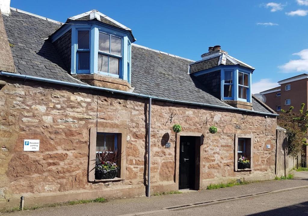 an old stone building with two windows on top of it at Ness City Cottage in Inverness