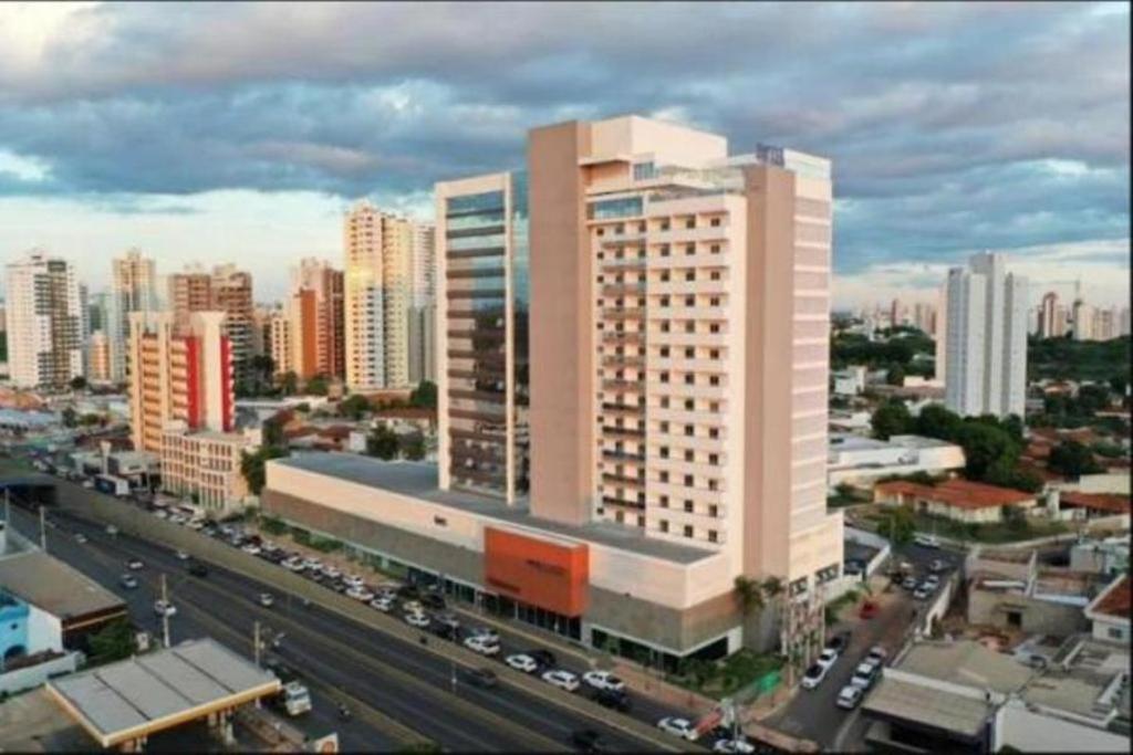 a large white building in a city with traffic at Advanced Hotel & Flats Cuiabá in Cuiabá