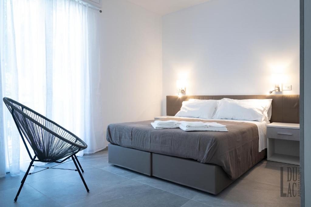 - une chambre avec un lit et une chaise noire dans l'établissement Du Lac Aparments, à Desenzano del Garda