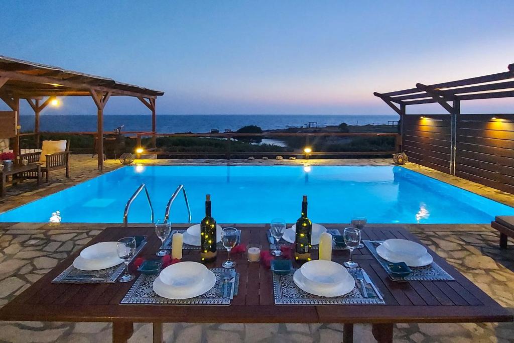 a dining table with wine bottles and glasses next to a swimming pool at CRYSTAL VILLAS in Lixouri