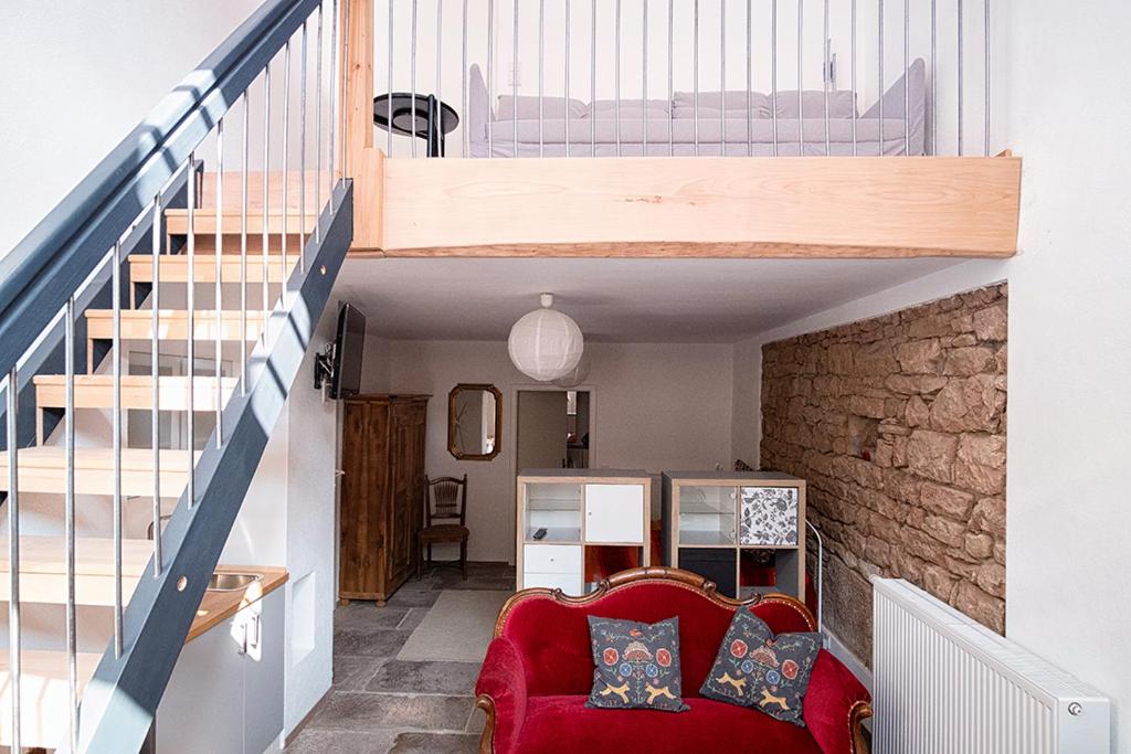 sala de estar con sofá rojo y escalera en Moderne Wohnung mit Studio in Bauernhausscheune am See en Biersdorf