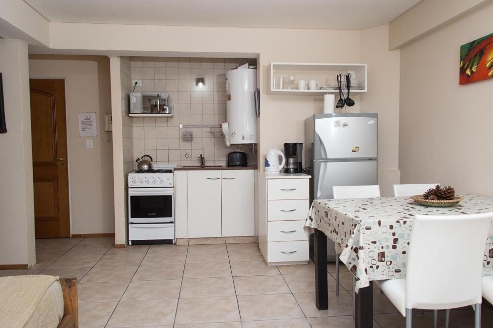 a kitchen with a table and a white refrigerator at DEPARTAMENTO CON EXCELENTE UBICACIÓN in San Carlos de Bariloche