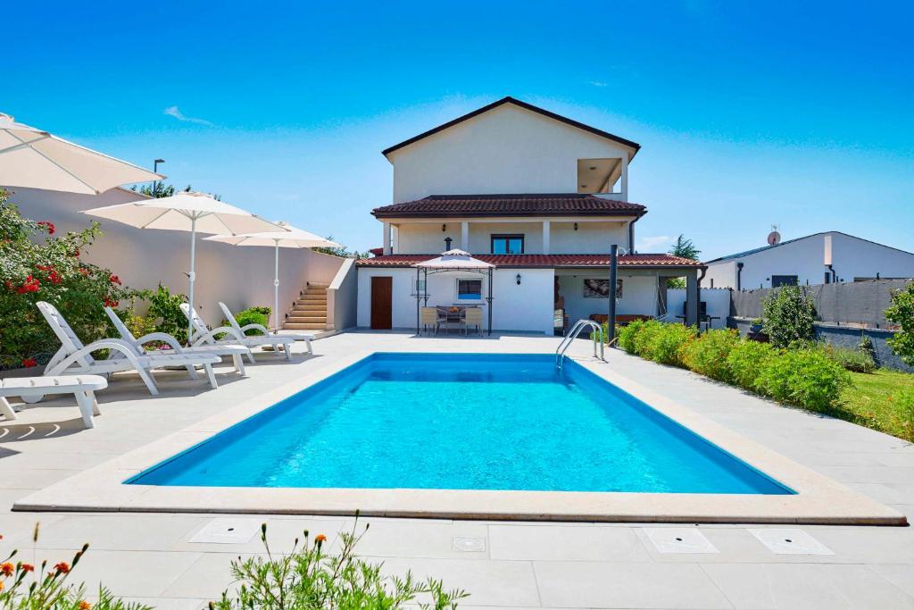 una villa con piscina frente a una casa en Holiday House Emma, en Burići
