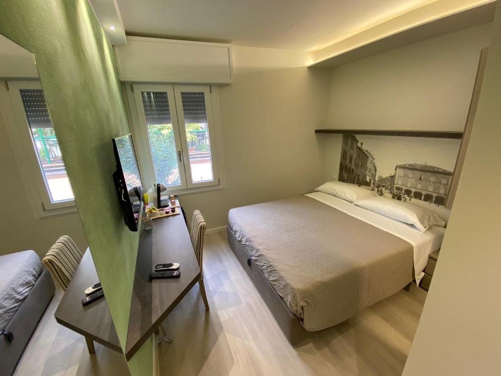 a bedroom with a bed and a table and two windows at Affittacamere Ventisettembre in Carpi