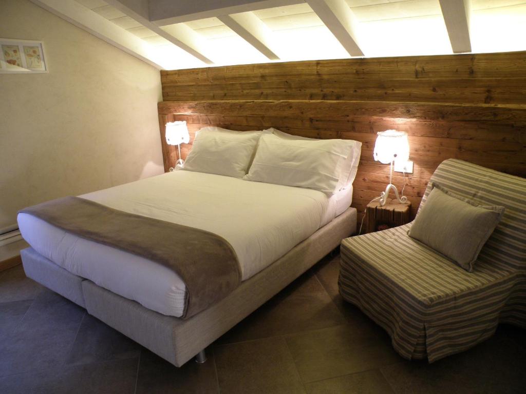 a bedroom with a large bed and a chair at La Vita in Campagna in Villa di Tirano