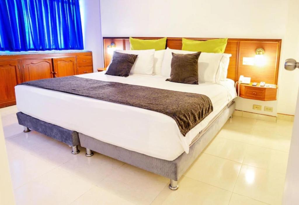een groot wit bed in een kamer met blauwe gordijnen bij Hotel Thama in Palmira