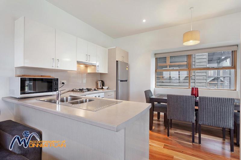 a kitchen with white cabinets and a table and chairs at Zoncolan in Dinner Plain