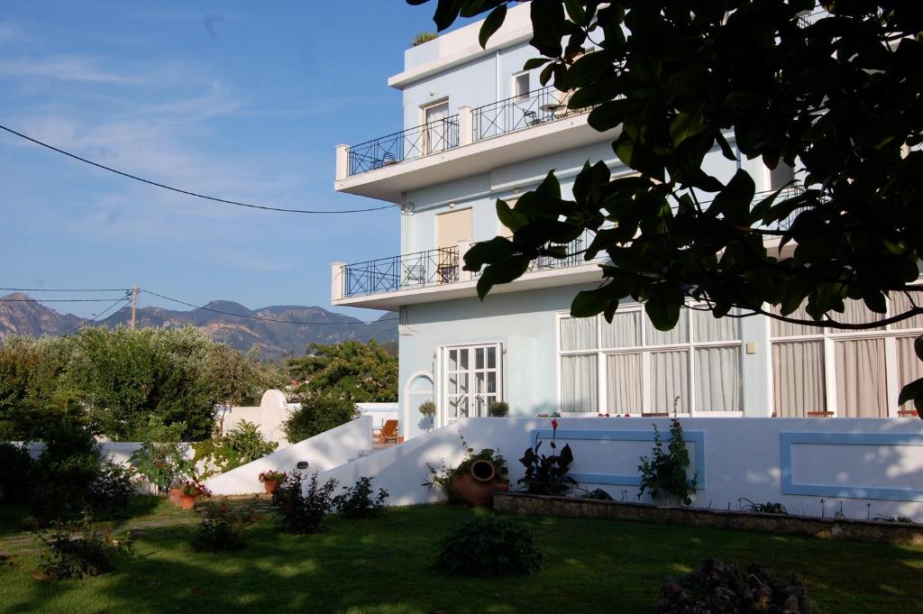 un edificio blanco con un patio delante en Astir Hotel, en Karlovasi