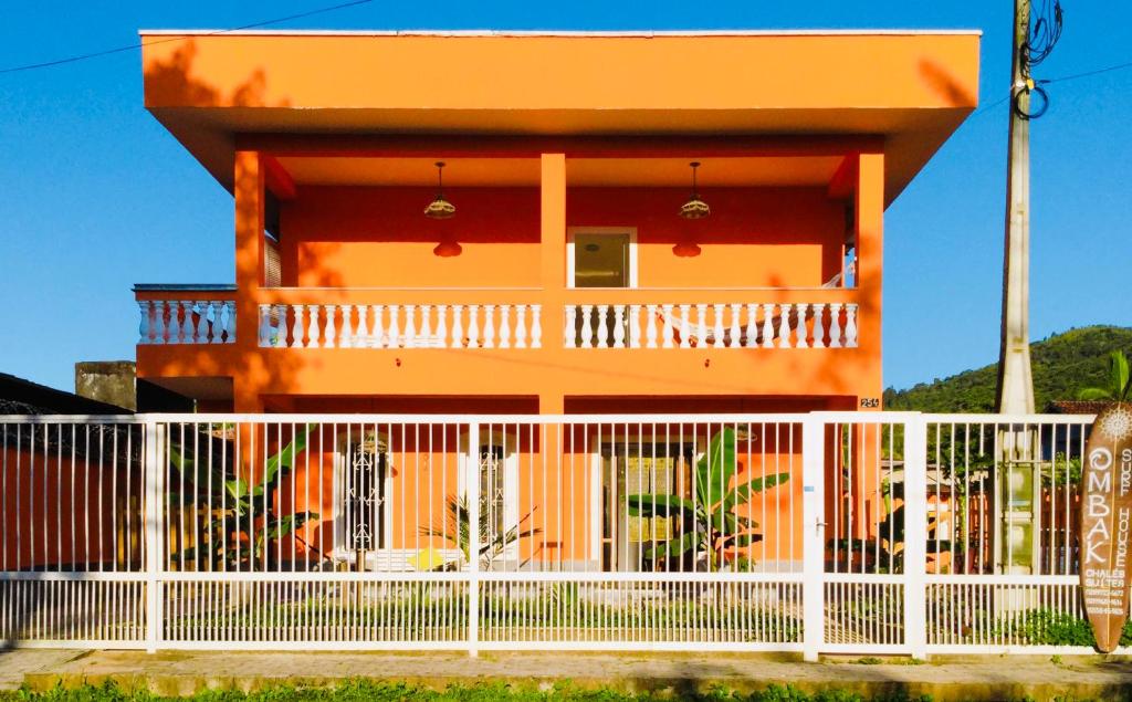an orange house with a white fence in front of it at Ombak Guest House in Ubatuba