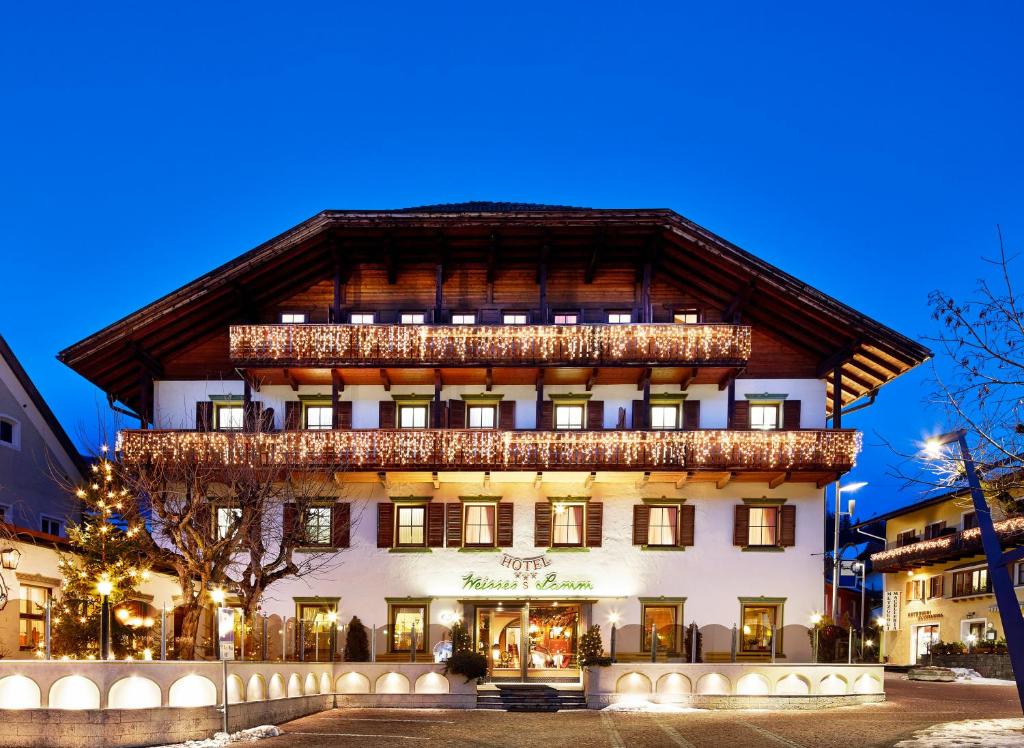 a large building with a balcony on top of it at Hotel Weisses Lamm in Monguelfo