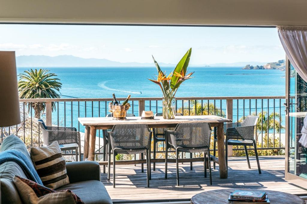 un tavolo e sedie su un balcone con vista sull'oceano di 16 Waikare - You've Got It Maid a Oneroa