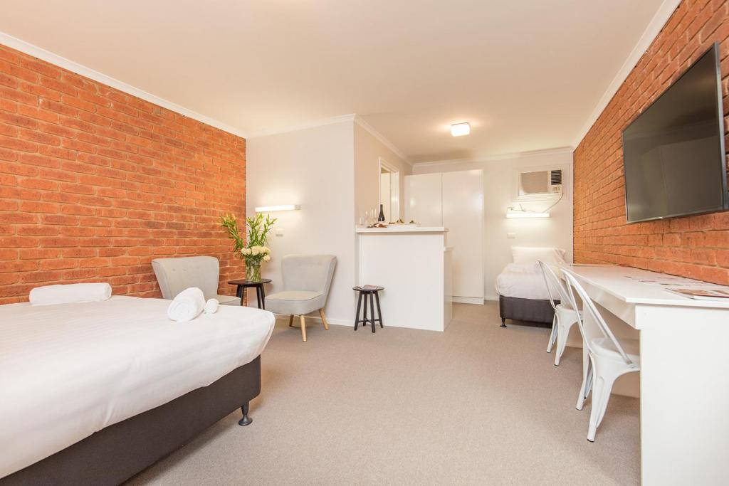 a room with two beds and a brick wall at Mildura City Gate Motel in Mildura