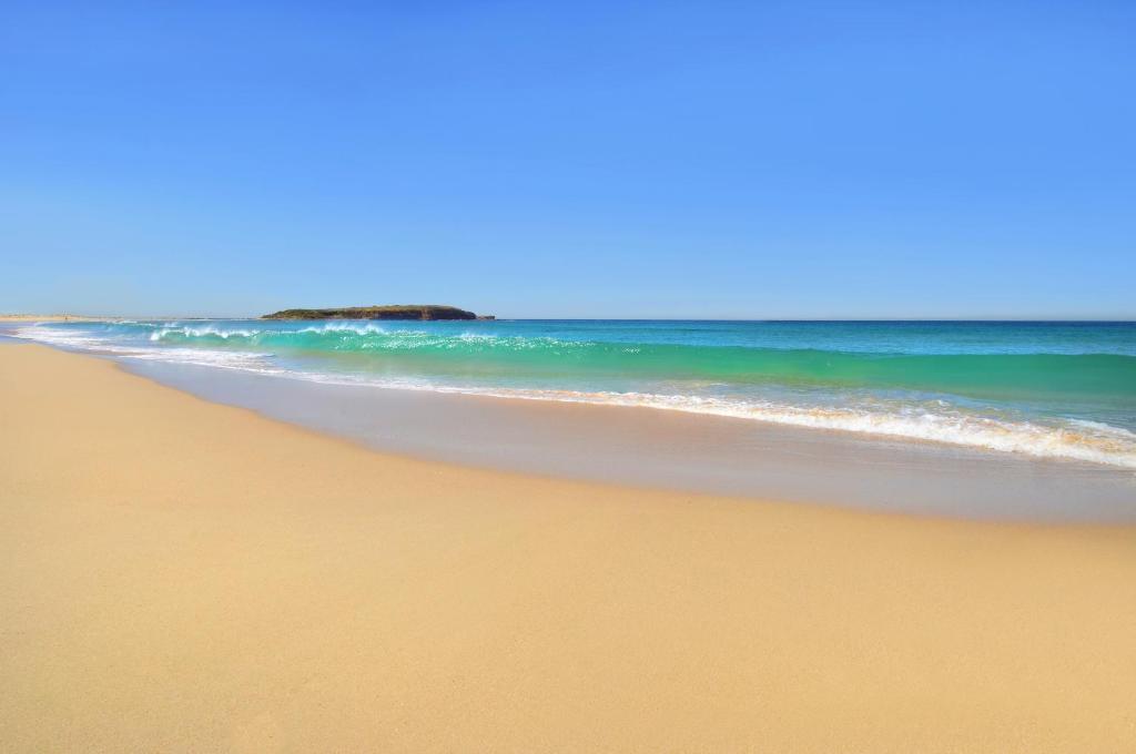 a view of a sandy beach with the ocean at Warilla Sands in Lake Illawarra