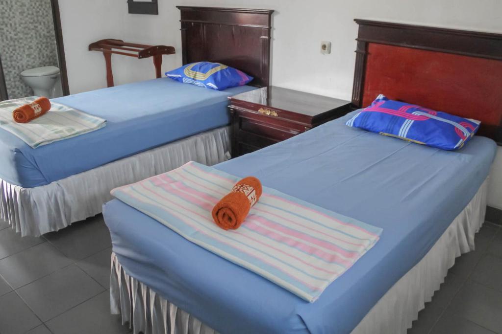 2 letti con asciugamani in una stanza di Hotel Rajawali Mitra RedDoorz a Cirebon