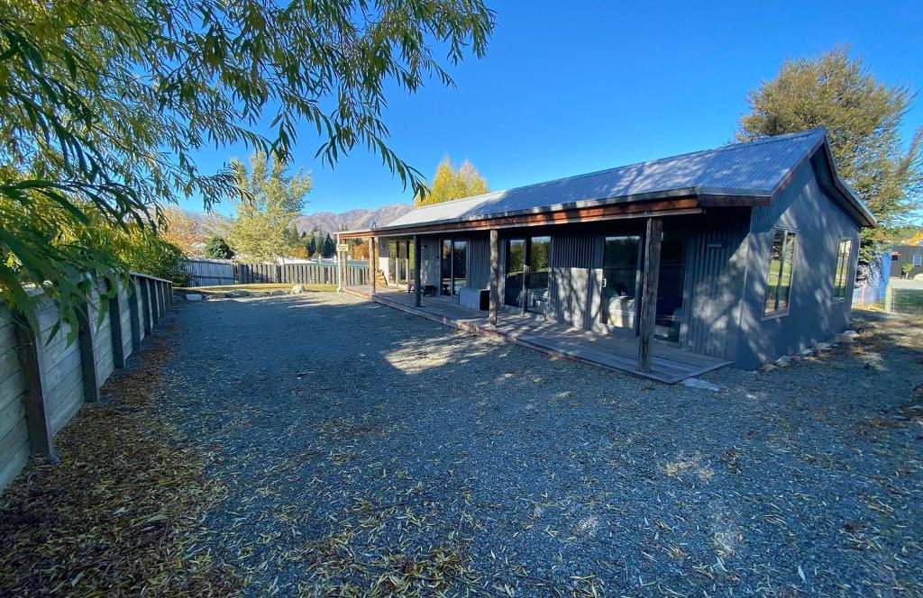 a house with a gambrel roof on a gravel yard at Ribbonwood Cottage in Lake Tekapo
