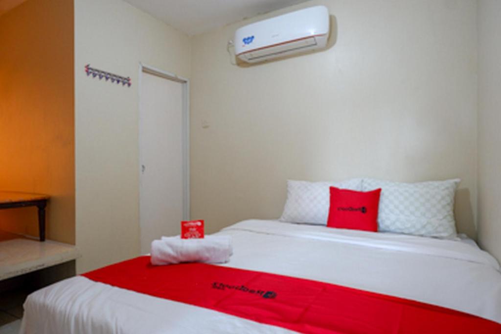 a bedroom with a white bed with red pillows at RedDoorz near RSUD dr Loekmono Hadi Kudus in Kudus
