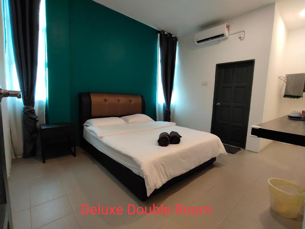 a bedroom with a bed and a green wall at Bilek@KADOK in Kota Bharu