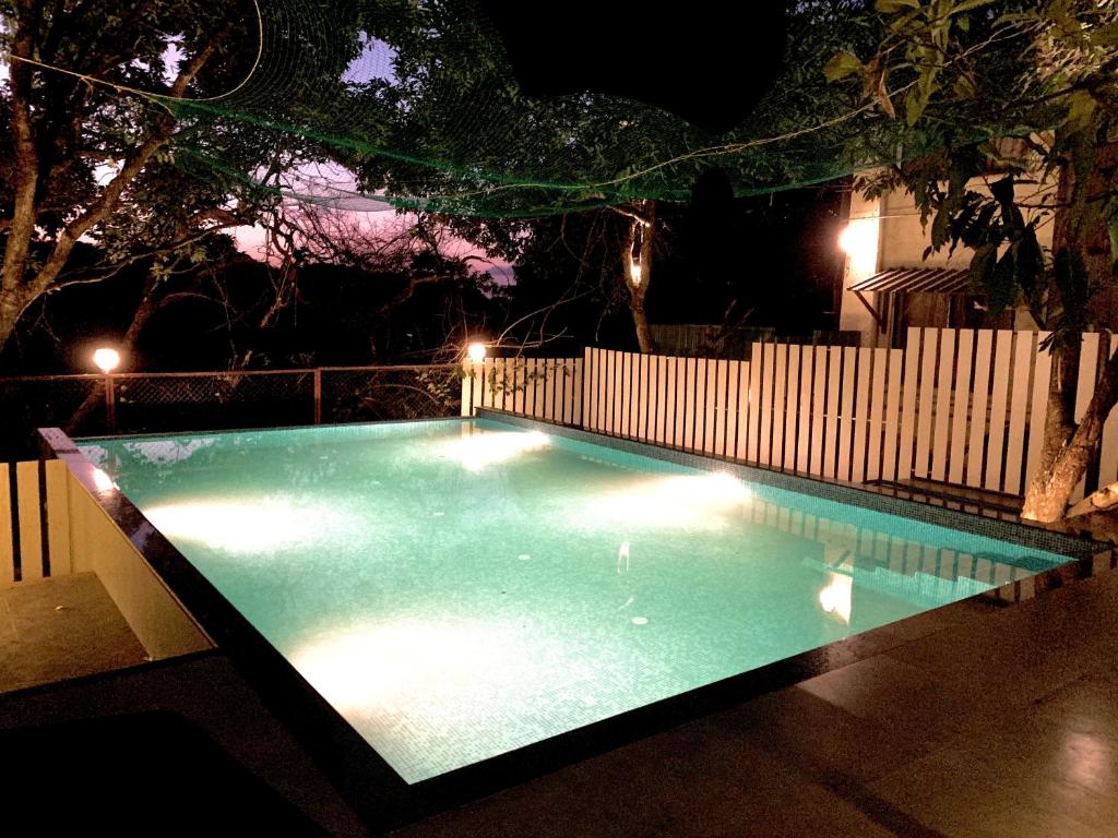 an empty swimming pool at night with a fence at Honeywood Holiday Homes in Mahabaleshwar