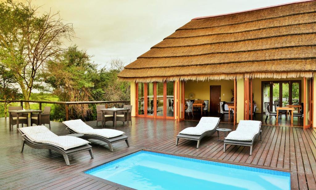 a pavilion with a pool and chairs and a house at Shishangeni by BON Hotels, Kruger National Park in Komatipoort