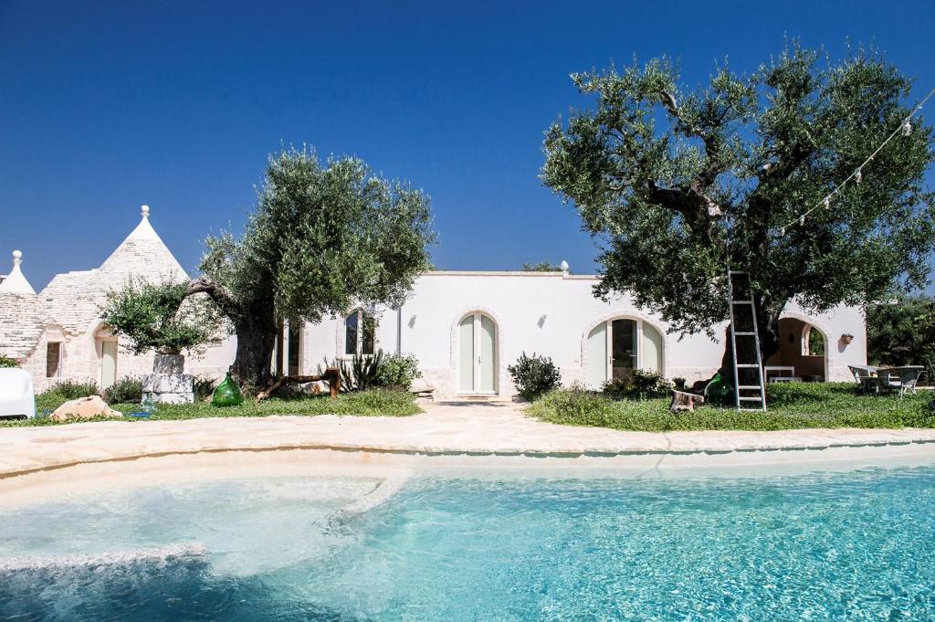 a white house with a swimming pool in front of it at Dimora Trullivo, Charming House in Castellana Grotte