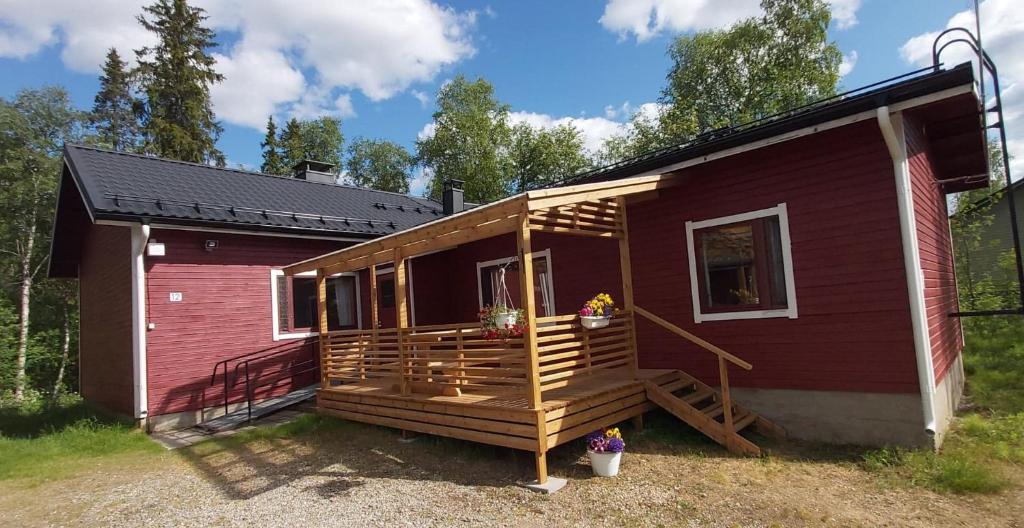 a small red house with a porch and a deck at Holiday Home Ivalo in Ivalo